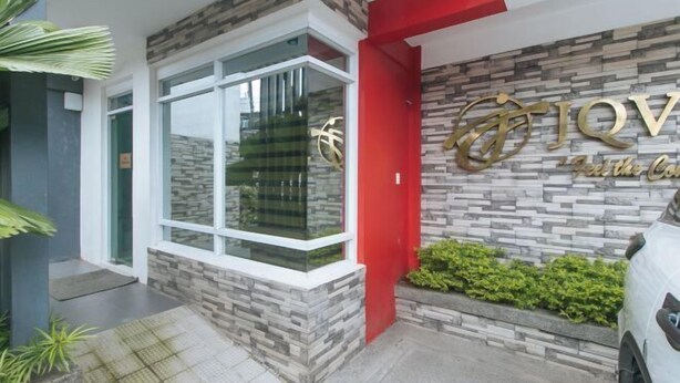 A modern building entrance with a stone facade, a glass window, and a red door. - RedDoorz @ JQV HOTEL Camarin Caloocan (Caloocan)