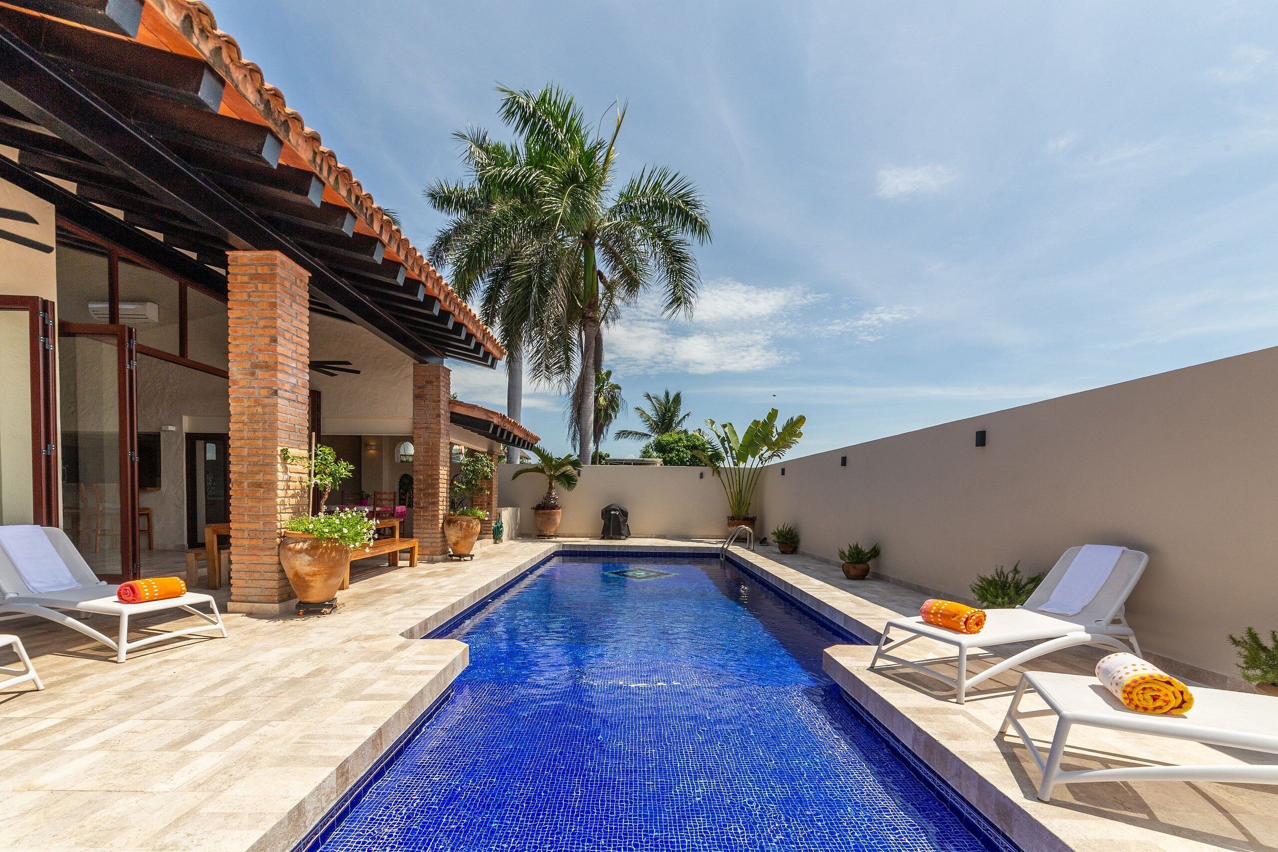 A swimming pool with lounge chairs and potted plants.