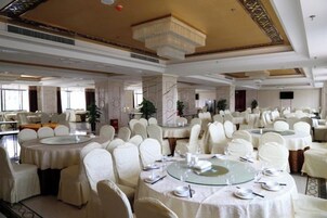Un salón de banquetes con mesas redondas, manteles blancos y sillas a juego.