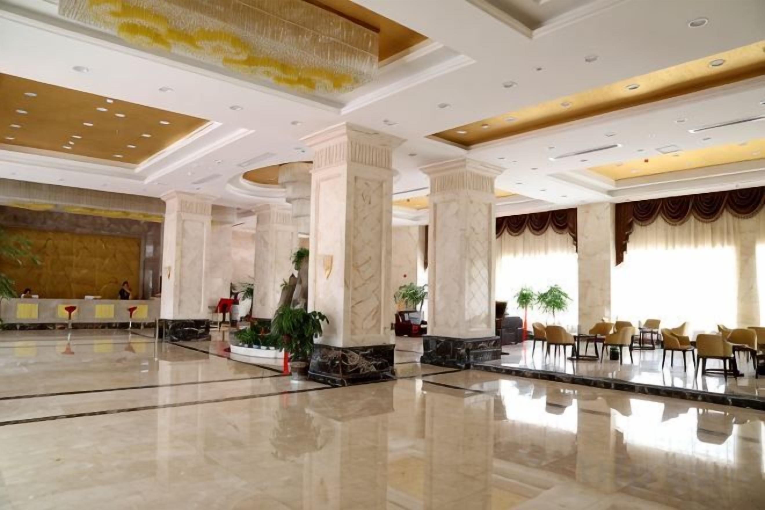 A spacious lobby with marble floors, large columns, and a reception desk.