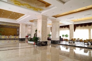 A spacious lobby with marble floors, large columns, and a reception desk.
