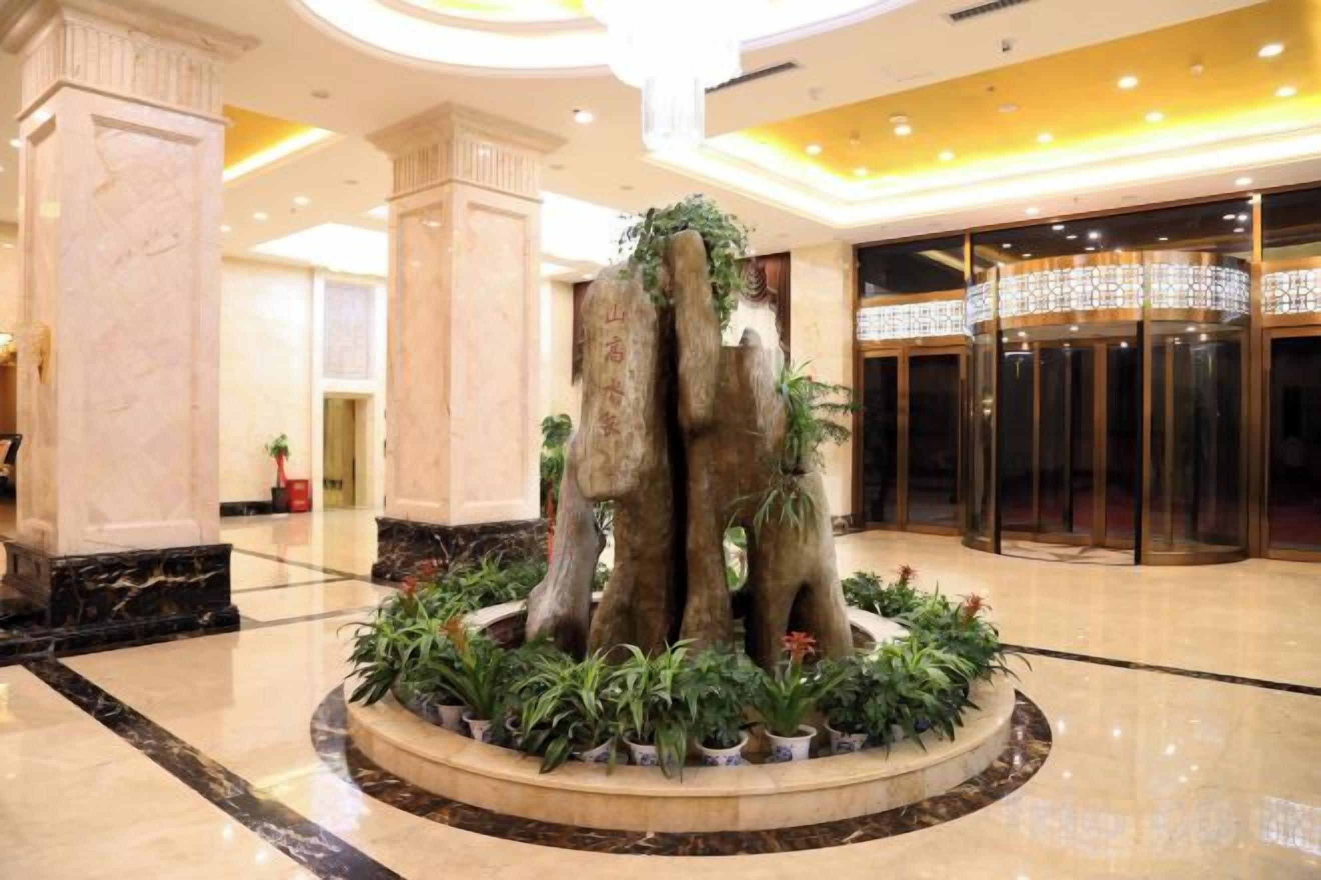 A lobby with a central fountain, marble columns, and a revolving door.