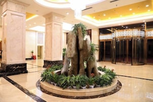 A lobby with a central fountain, marble columns, and a revolving door.