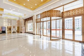 A spacious lobby with a polished floor, large glass doors, and a decorative wooden panel. - Jiangang Hotel (Qianshan)