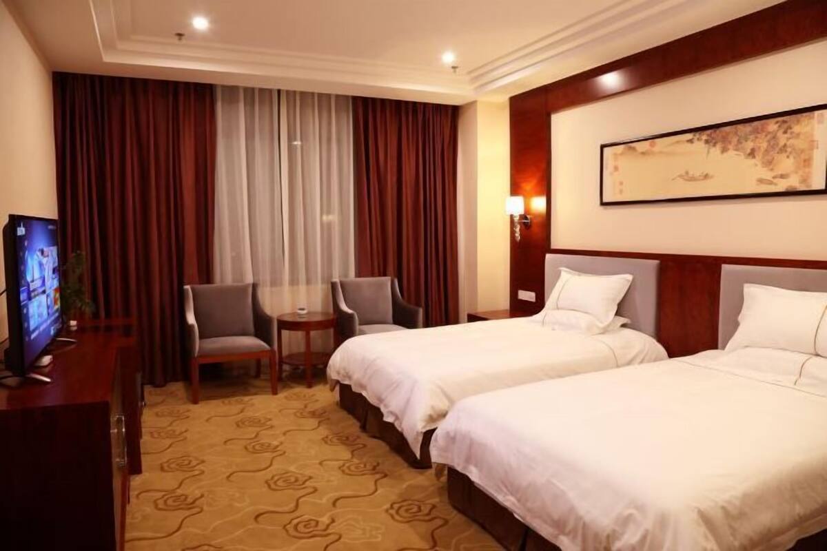 Une chambre d’hôtel avec deux lits, une télévision, une petite table et une chaise.