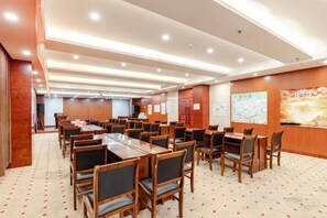 A conference room with multiple tables and chairs, wooden walls, and a carpeted floor. - Jiangang Hotel (Qianshan)