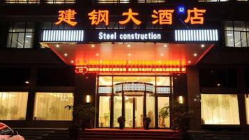 A hotel entrance with a sign indicating 'Steel construction' and a large illuminated sign above the entrance.