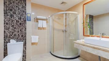 Un baño moderno con cabina de ducha de vidrio, inodoro blanco y un espejo grande sobre un lavamanos.