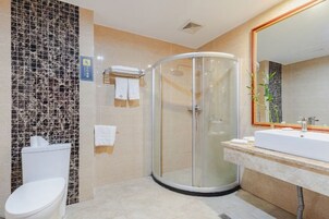 Un baño moderno con cabina de ducha de vidrio, inodoro blanco y un espejo grande sobre un lavamanos.