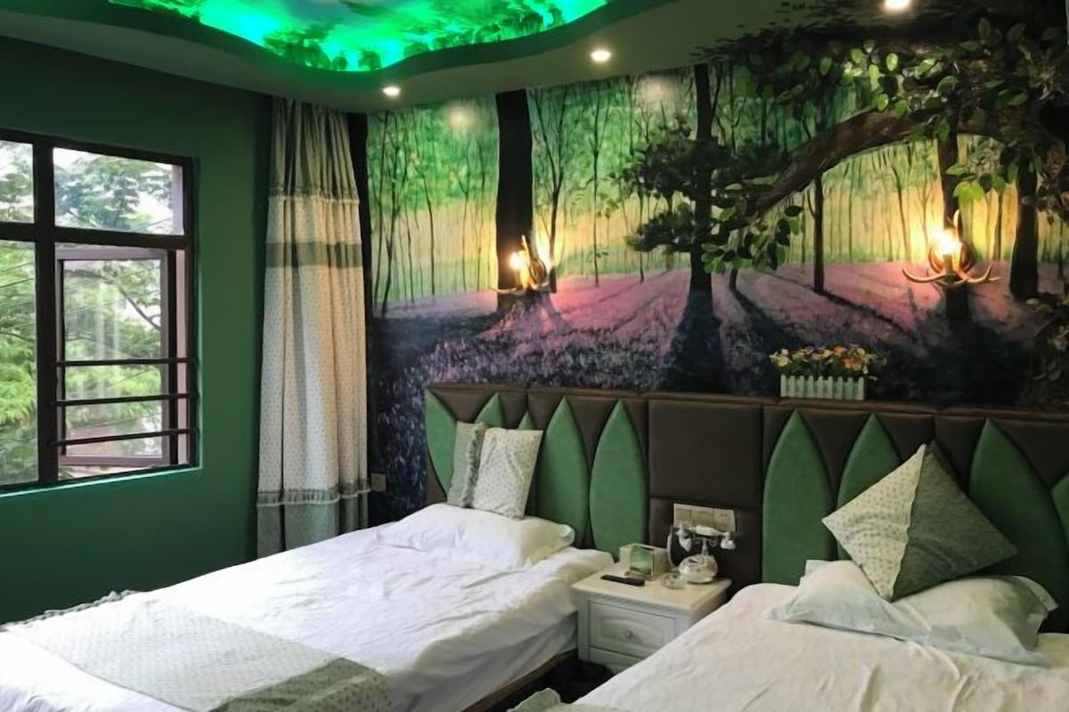 Une chambre avec deux lits, une fresque représentant une scène de forêt et une fenêtre avec des rideaux.