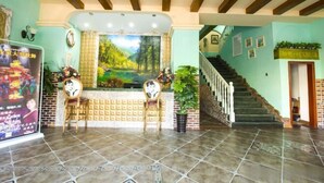 Zona de recepción con un mural, una escalera y un mostrador.