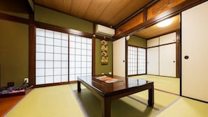 Una habitación con esteras de tatami, una mesa de madera baja, puertas correderas y un tapiz tradicional japonés.