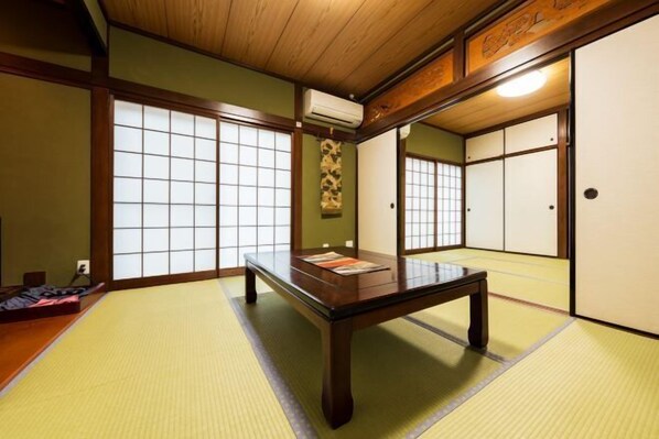 Et rum med tatamimåtter, et lavt træbord, skydedøre og en traditionel japansk vægtekstil.