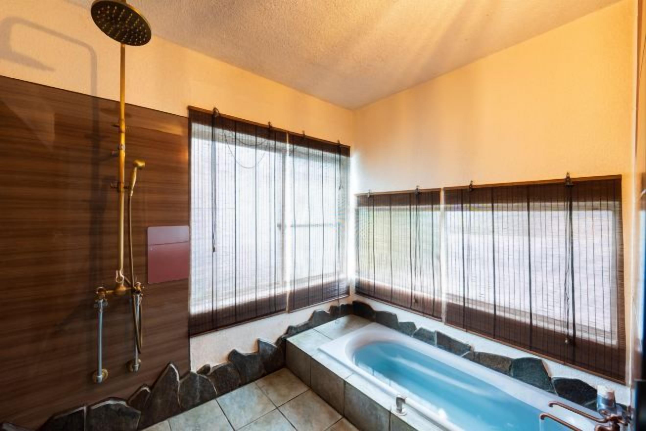 A modern bathroom with a bathtub, shower, and large windows.