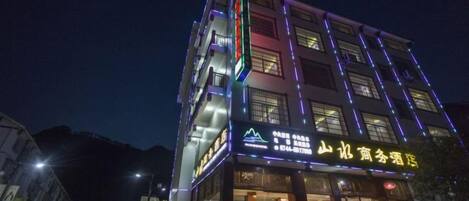 Un hotel de varios pisos con señalización iluminada y una entrada visible.