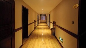 Un pasillo de hotel con pisos de madera, puertas a ambos lados y un cartel que indica la habitación 438.