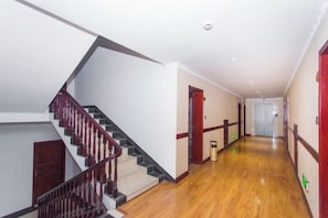 A hallway with a wooden floor, a staircase with a red railing, and doors with red trim. - Shanshui Business Hotel (Zhangjiajie)