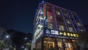 Un hotel de varios pisos con señalización iluminada y una entrada bien iluminada.