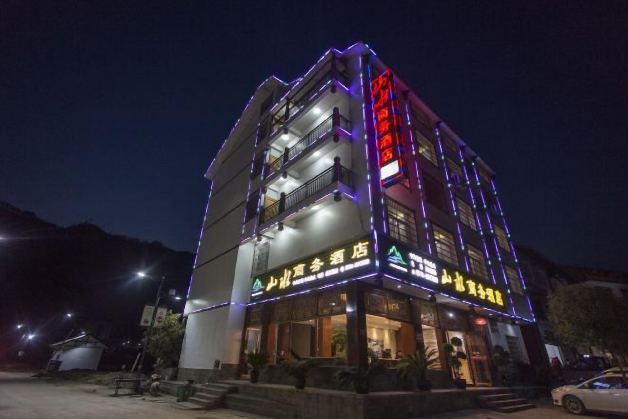 Um hotel com vários andares, fachada iluminada e entrada visível.