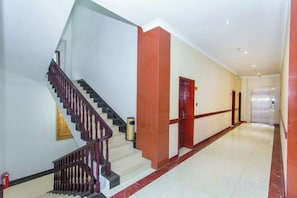 A hotel corridor with a staircase, a door, and a tiled floor. - Shanshui Business Hotel (Zhangjiajie)