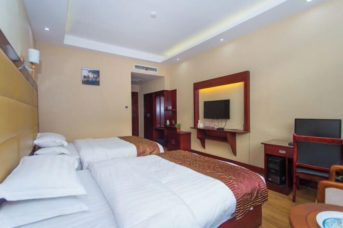A hotel room with two beds, a TV, a desk, and a chair.