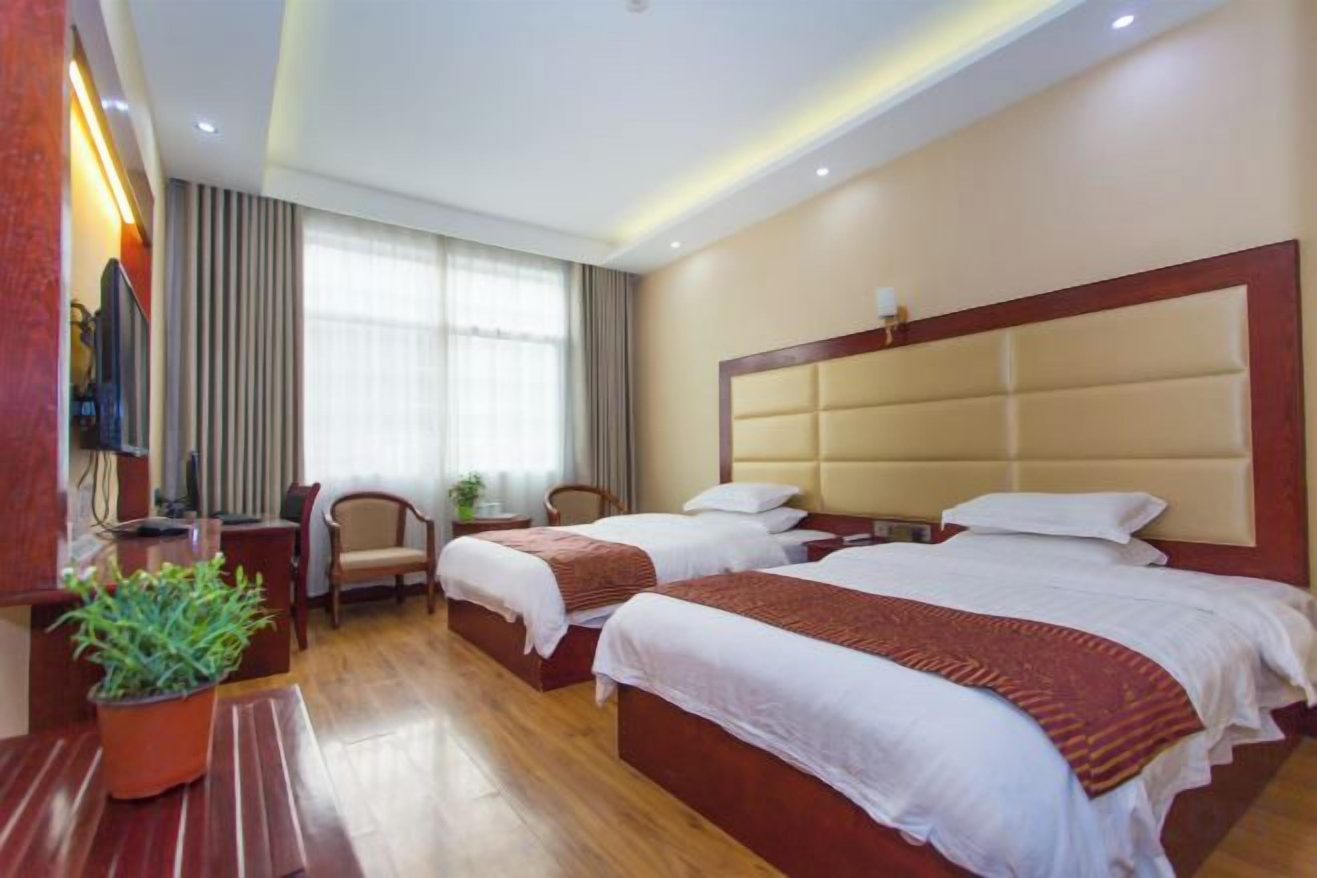 Ein Hotelzimmer mit zwei Betten, einem Schreibtisch, einem Sessel und einem Fernseher.
