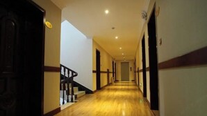 Un largo pasillo estrecho con suelo de madera y una escalera a la izquierda.