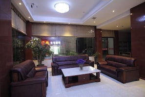 A hotel lobby with leather sofas, a coffee table, and a large window. - Shanshui Business Hotel (Zhangjiajie)