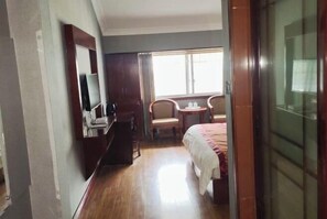 A hotel room with a bed, a desk with a computer, a chair, and a small table with a lamp. - Shanshui Business Hotel (Zhangjiajie)