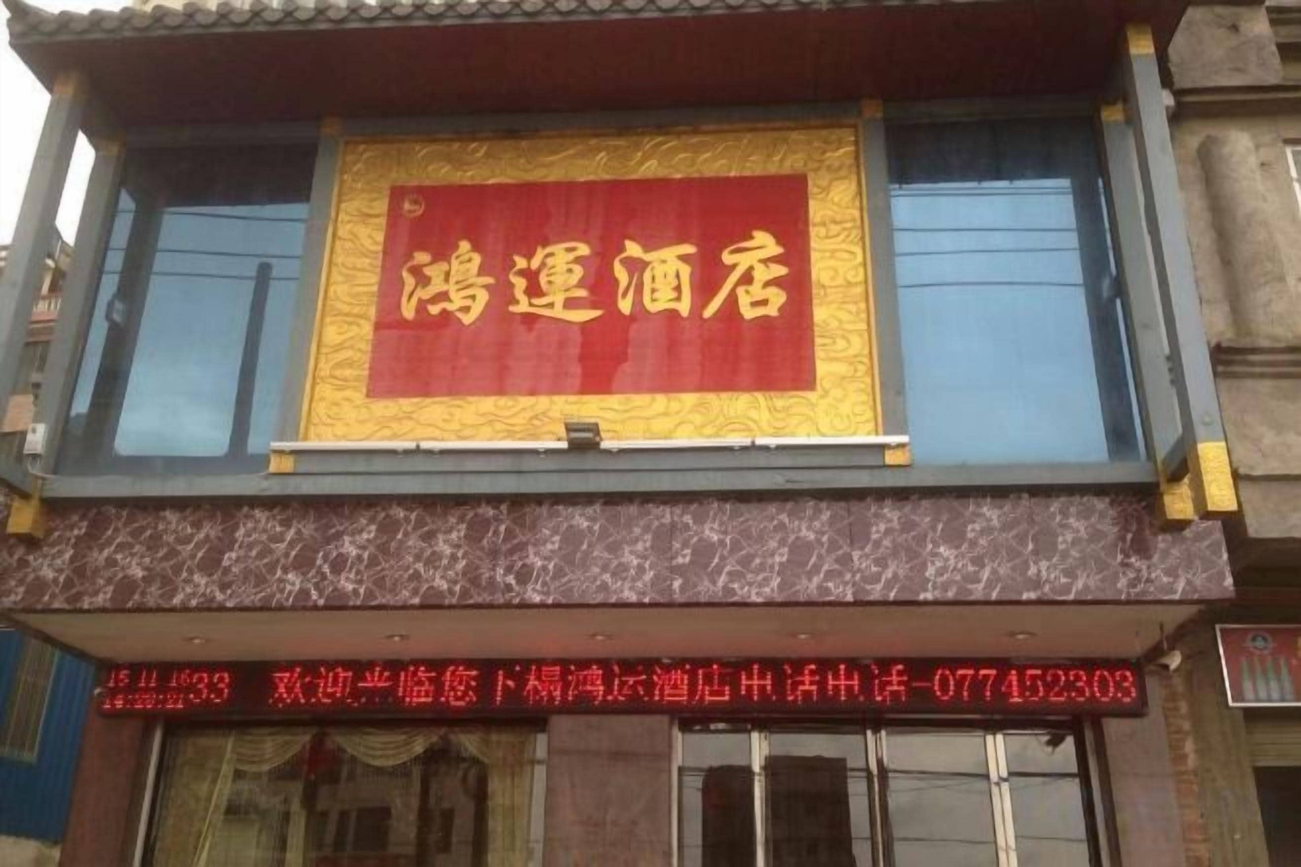 A hotel with a prominent red and gold signboard.