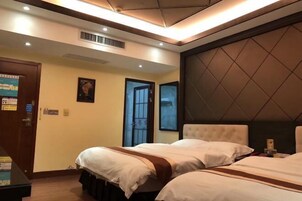 Habitación de hotel con dos camas, un cabecero grande y acolchado, una puerta con un letrero y una ventana con vistas.