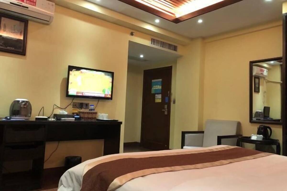 A hotel room with a bed, a desk with a computer, a television, and a mirror.