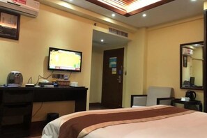 A hotel room with a bed, a desk with a computer, a television, and a mirror. - Hongyun Hotel (Hezhou)