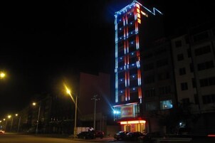 Un edificio alto con señalización iluminada en la noche.