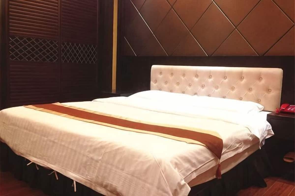 A neatly made bed with a white headboard, a wooden nightstand with a red object, and a patterned wall.