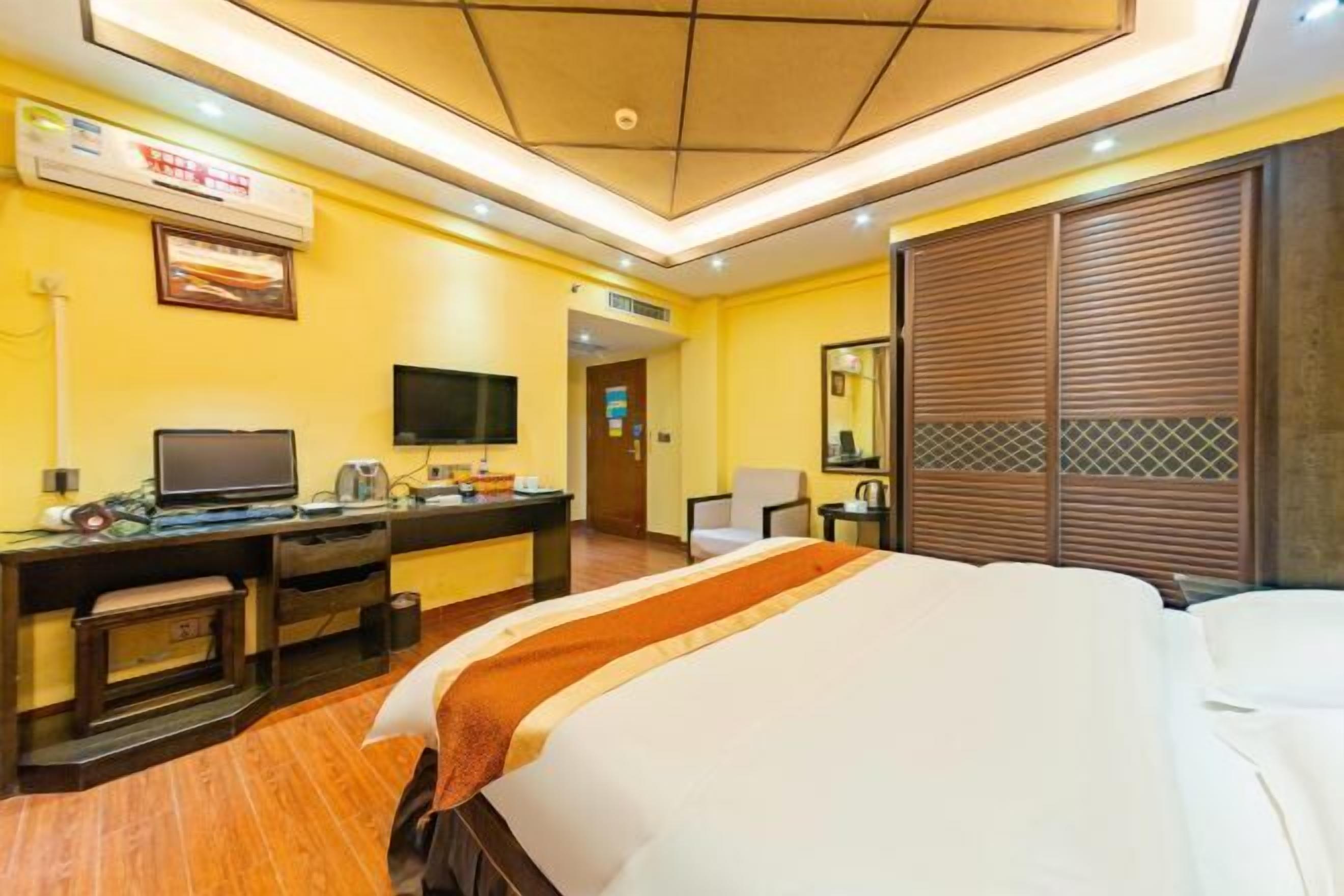 Habitación de hotel con cama, escritorio, televisor y espejo.