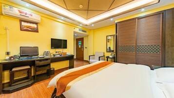 Habitación de hotel con cama, escritorio, televisor y espejo.