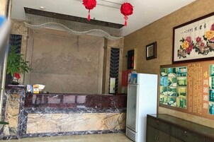 Zona de recepción con mostrador de mármol, un refrigerador y una pared decorada con obras de arte enmarcadas.