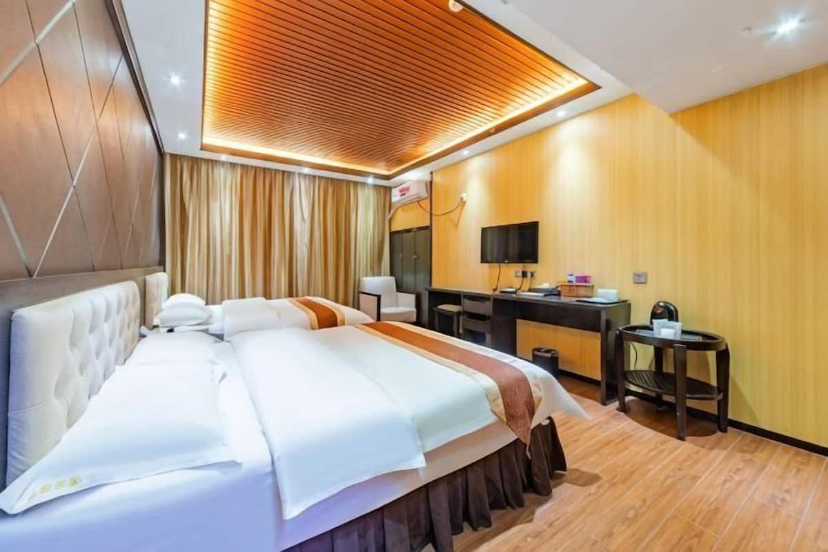 A hotel room with a large bed, a desk, a chair, and a television.