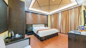 Hotellihuone, jossa on sänky, työpöytä, peili, lipasto ja katto, jossa on geometrinen kuvio.