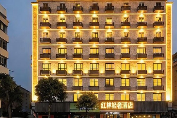 A multi-story hotel with evenly spaced balconies and a row of illuminated windows. - Honglin Hotel (Foshan)