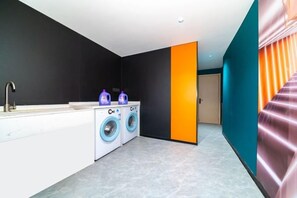 A modern laundry room with a sink, two washing machines, and a door leading to another room. - Honglin Hotel (Foshan)