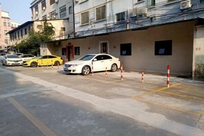 A street view with parked cars and a building with multiple windows and balconies. - Honglin Hotel (Foshan)