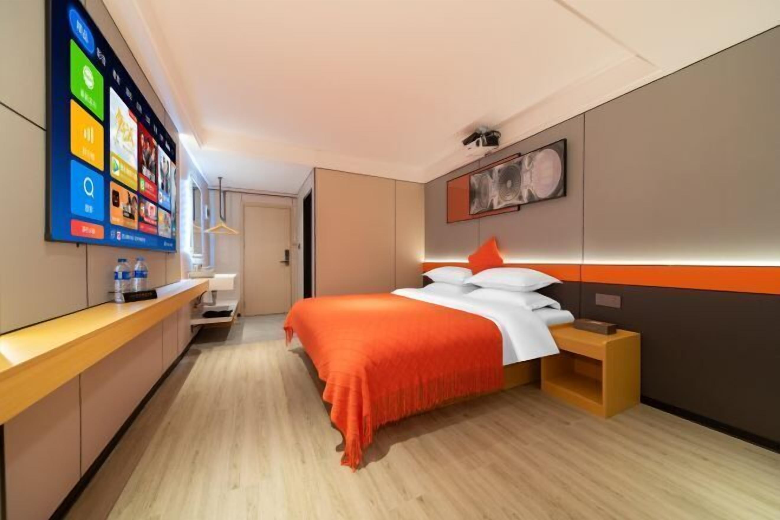 Ett modernt hotellrum med en säng, ett sängbord, en tv som är monterad på väggen och ett trägolv.