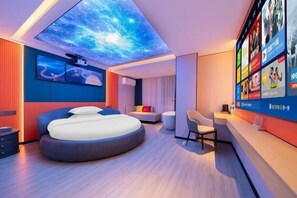 A modern hotel room with a curved bed, a galaxy-themed ceiling, a wall-mounted TV, and a seating area. - Honglin Hotel (Foshan)