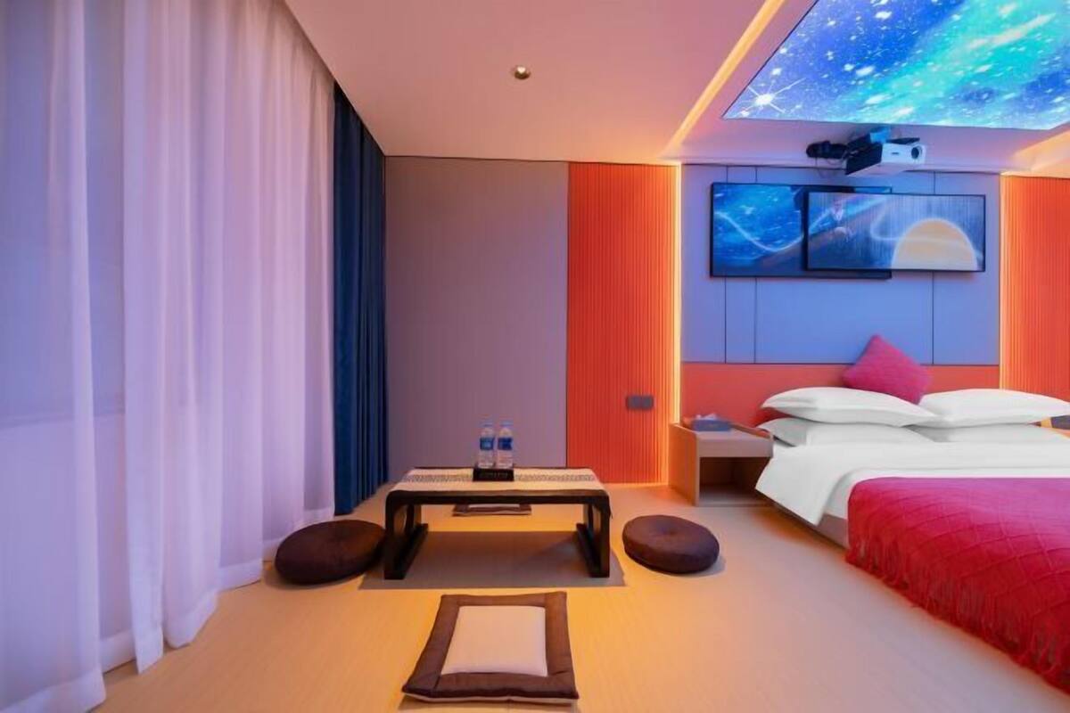 A modern hotel room with a bed, a desk, and a wall-mounted TV.