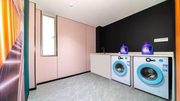 A laundry room with two washing machines, a sink, and a window.