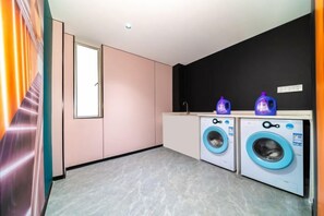 Een wasserette met twee wasmachines, een wasbak en een raam.