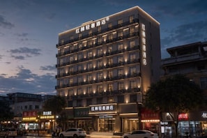 Et hotel med flere etager, en moderne facade, flere balkoner og en indgang i stueplan.