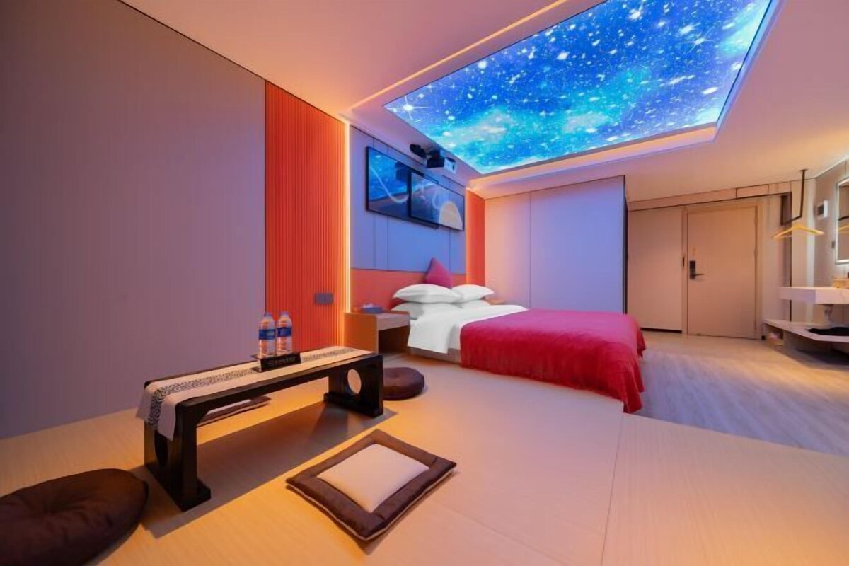 A modern bedroom with a skylight, a bed, a bedside table, and a bench.